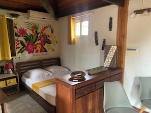 Une chambre à coucher comprenant un lit, une table de chevet, une lampe et un mur orné d’un tableau floral.