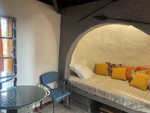 A small, cozy room with a bed, a chair, and a table.