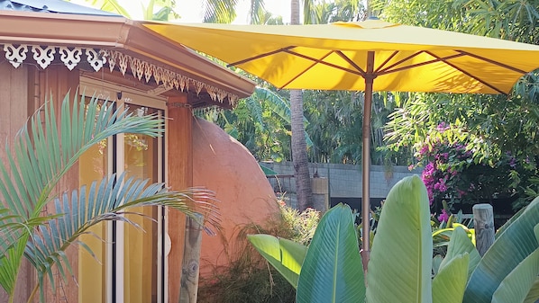 A building with a yellow umbrella, large green leaves, and a wooden structure.