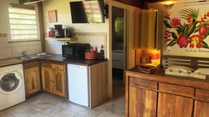 A compact kitchen with a washing machine, microwave, and a small refrigerator.