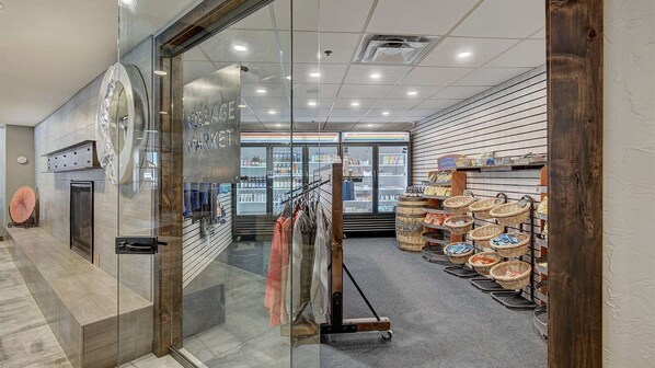A modern interior with a glass storefront, racks of clothing, and baskets of snacks.