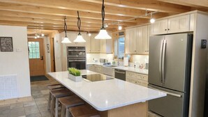 A modern kitchen with a large island, stainless steel appliances, and wooden bar stools.