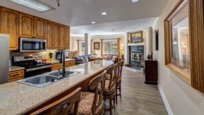 Una cocina amplia con armarios de madera, una isla central con taburetes de bar, un microondas integrado y una estufa.