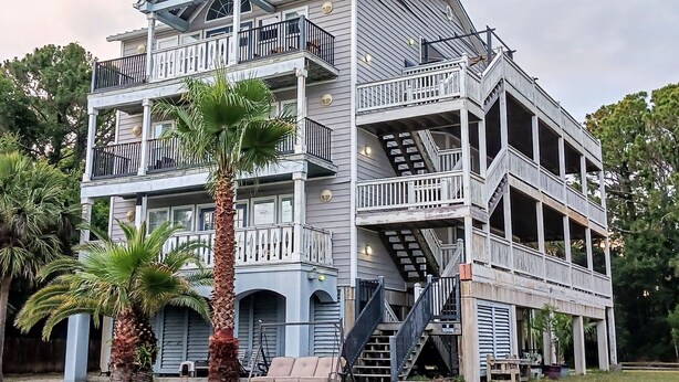 Un edificio de varios pisos con balcones, escaleras y mobiliario exterior.