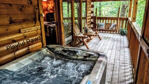 Een houten chalet met een hottub, houten terras en een bordje met de tekst 'Playful Paws'.