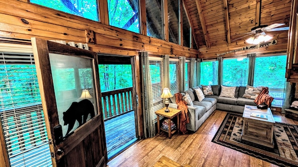 L’intérieur d’une cabane avec un plafond en bois, un canapé, une table basse et une cheminée.