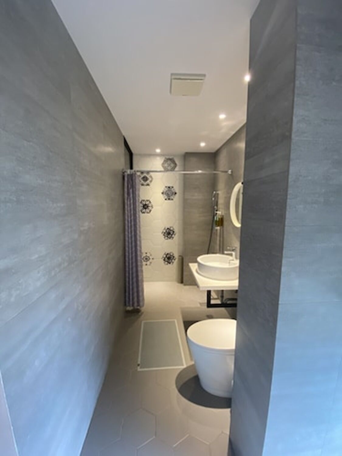 A modern bathroom with a shower, a toilet, and a sink.