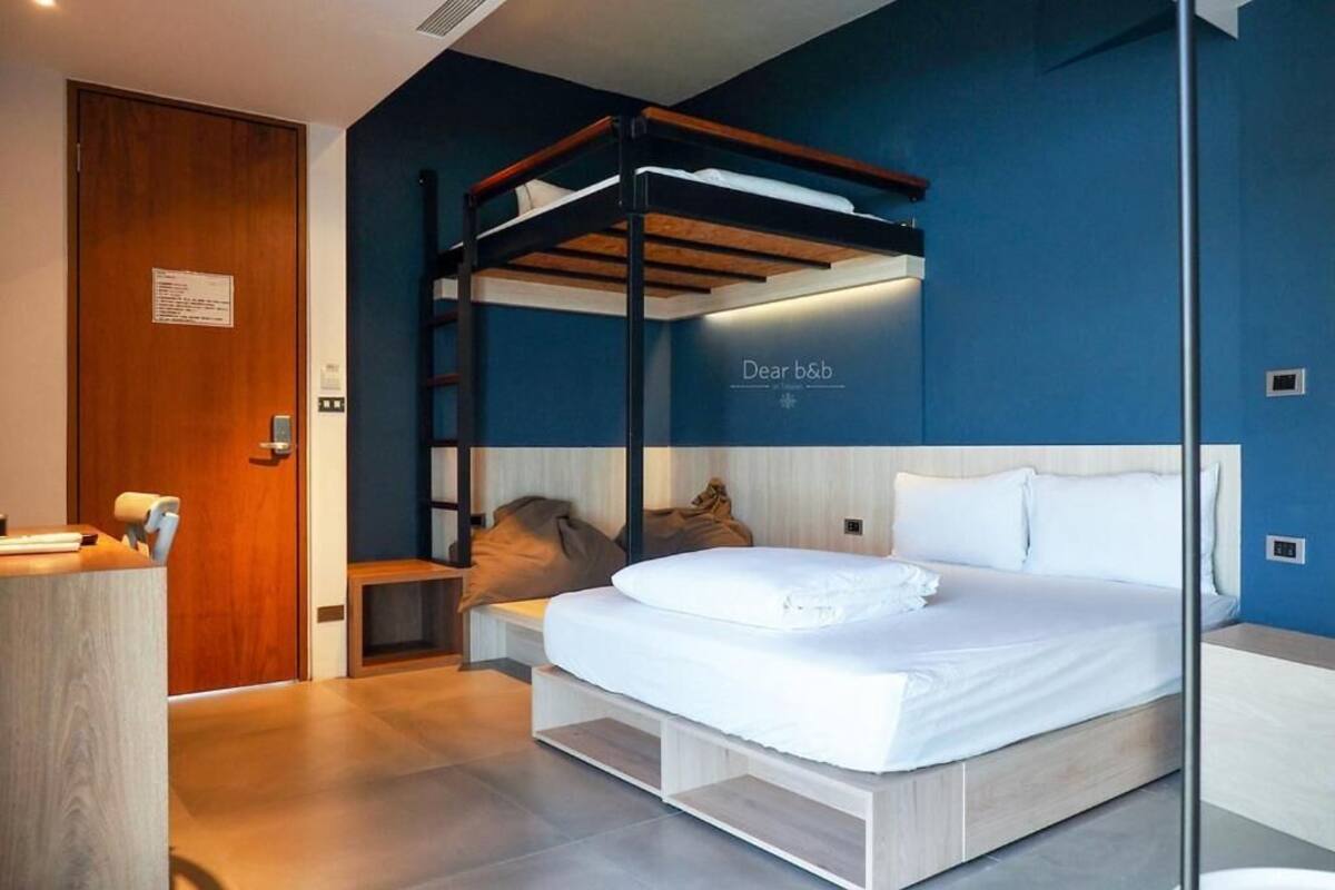 Een moderne slaapkamer met een stapelbed, een bureau met stoel en een nachtkastje.