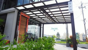 A covered outdoor area with a glass entrance, potted plants, and a sign reading "Dear b&b".