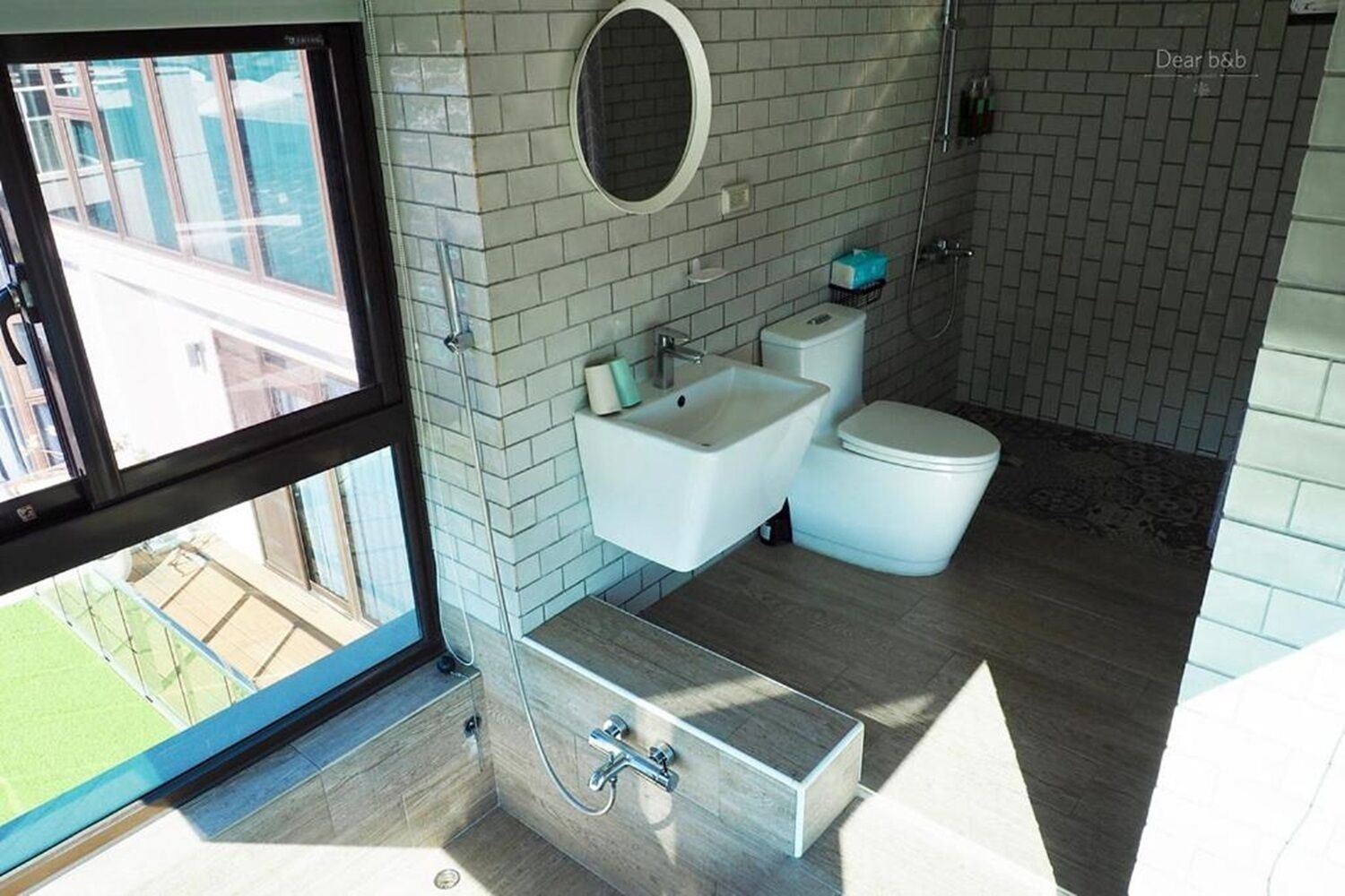 Un bany modern amb una finestra gran, un lavabo, un vàter i un lavabi.