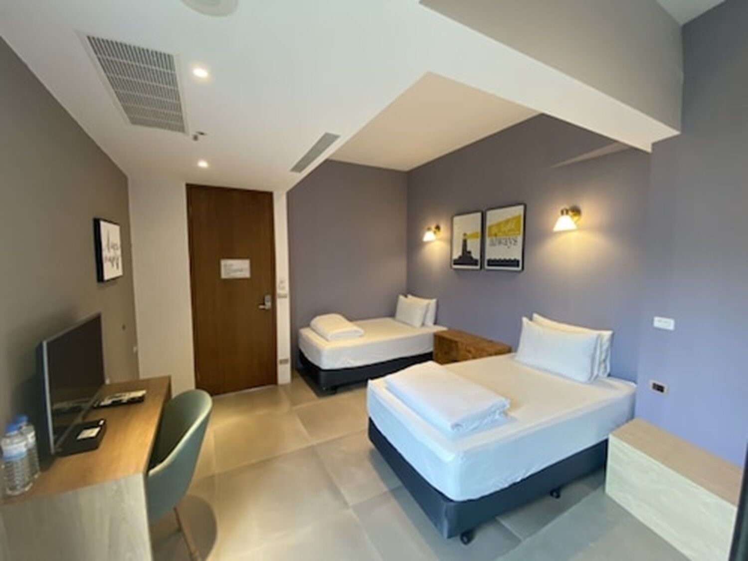 Habitación de hotel con escritorio, dos camas, una silla y televisión.