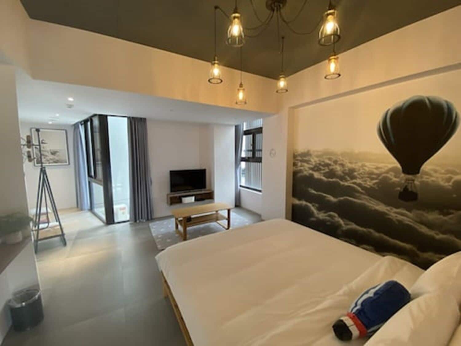 Una habitación de hotel moderna con una cama grande, un televisor y un mural de un globo aerostático.