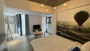 Una habitación de hotel moderna con una cama grande, un televisor y un mural de un globo aerostático.