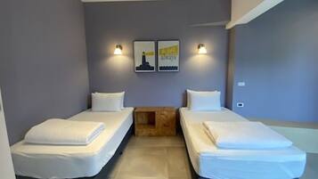 Una habitación con dos camas, una mesita de madera y dos lámparas fijadas a la pared.