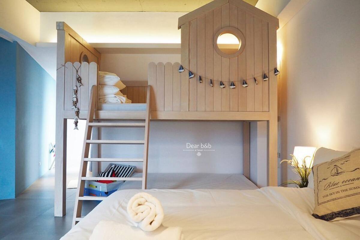 Een slaapkamer met een stapelbed, een klein bureau en een wandplank.