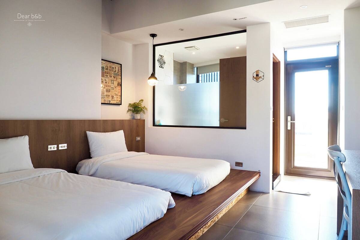 Een moderne hotelkamer met twee eenpersoonsbedden, een grote spiegel, een houten hoofdbord en een kleine kamerplant.