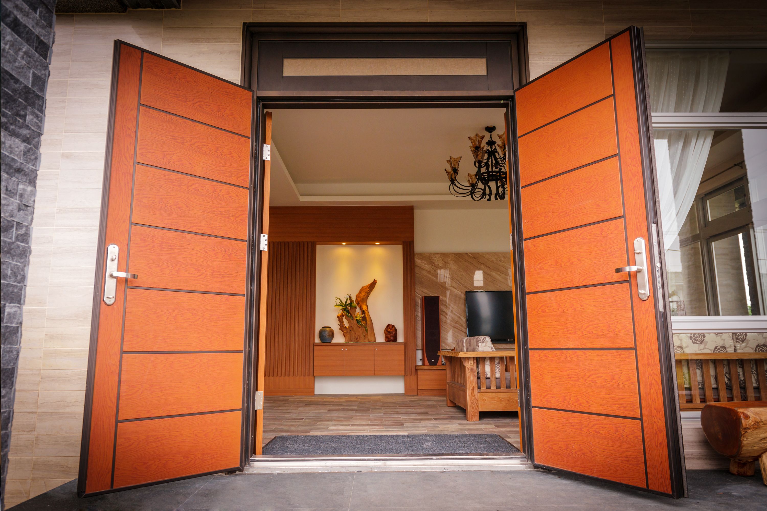 Una entrada moderna con puertas de madera, un banco y una televisión.