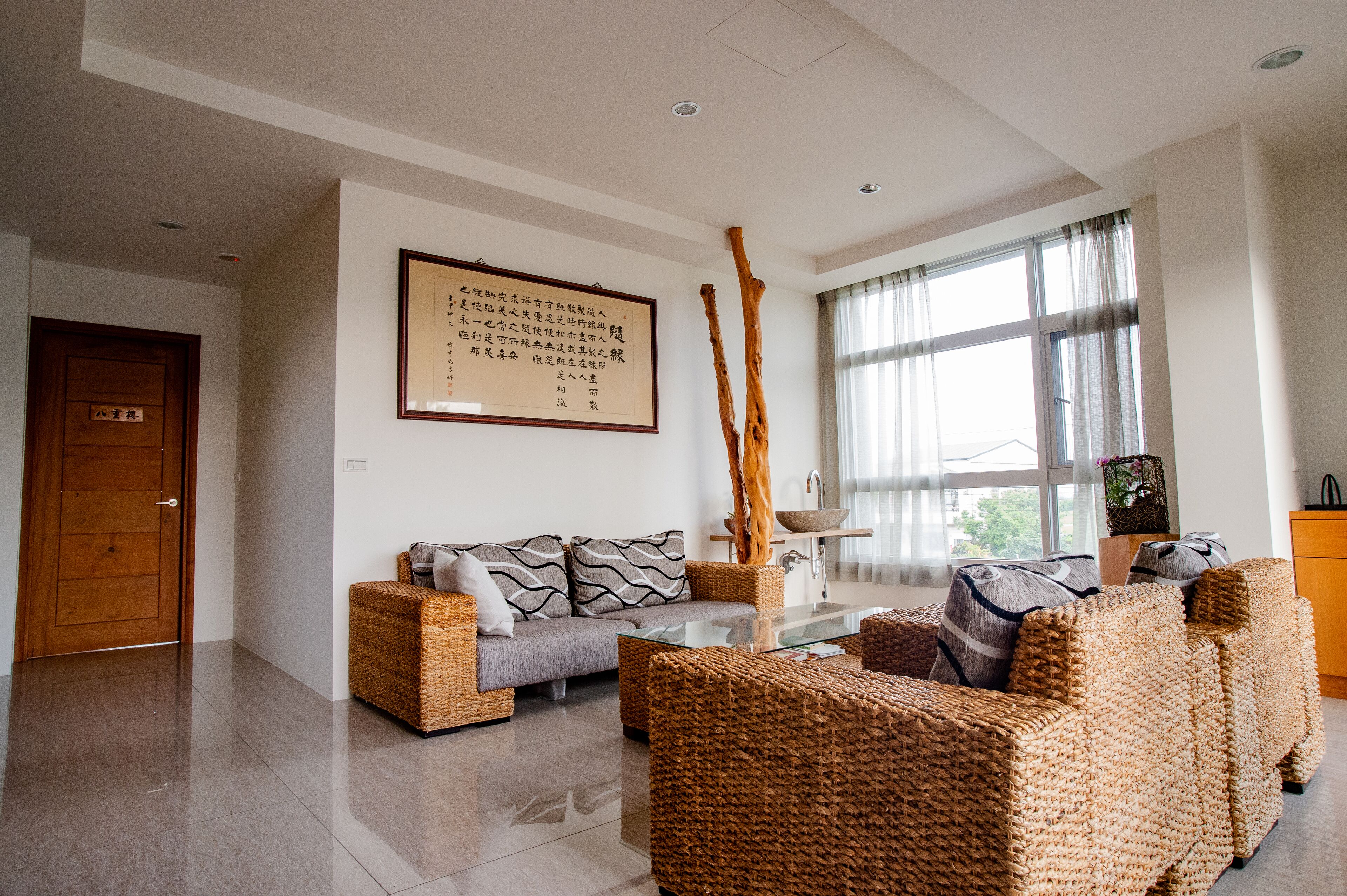 A modern living room with a sofa, two armchairs, a coffee table, and a large framed artwork on the wall.
