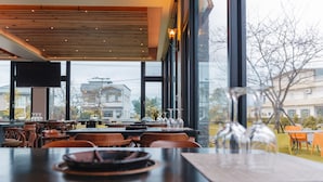 Un restaurante con un amplio ventanal, techo de madera y vistas a edificios.