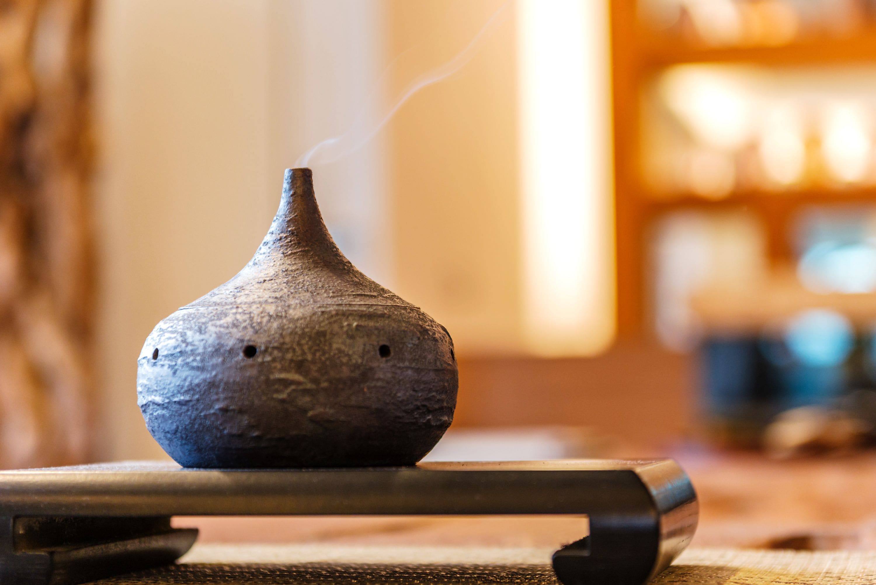 Un petit pot en céramique à la texture particulière, d’où s’échappe de la vapeur, posé sur une surface en bois.
