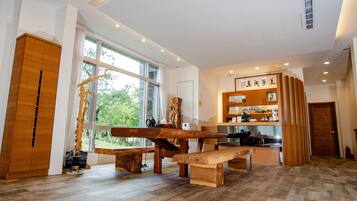 Une pièce spacieuse avec une grande table en bois, une armoire en bois et une vue sur la verdure environnante.
