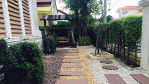 A garden pathway with stepping stones leading to a wooden pergola. - Bann Dao (Lam Luk Ka)