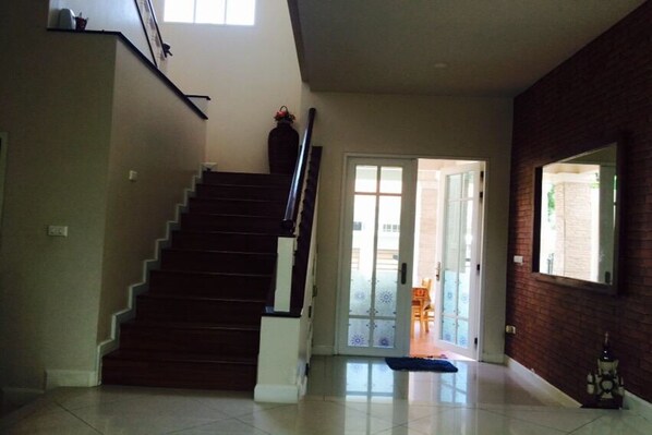 A staircase leading to a landing with a door to an outdoor area. - Bann Dao (Lam Luk Ka)