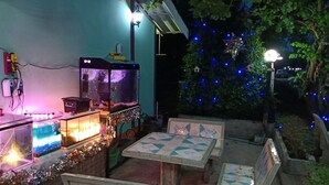 A patio area with a fish tank, outdoor seating, and decorative lights. - Suansuppachok Inn (Ongkharak)