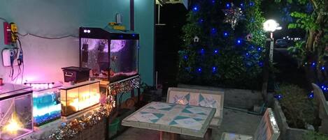 A patio area with a fish tank, outdoor seating, and decorative lights.