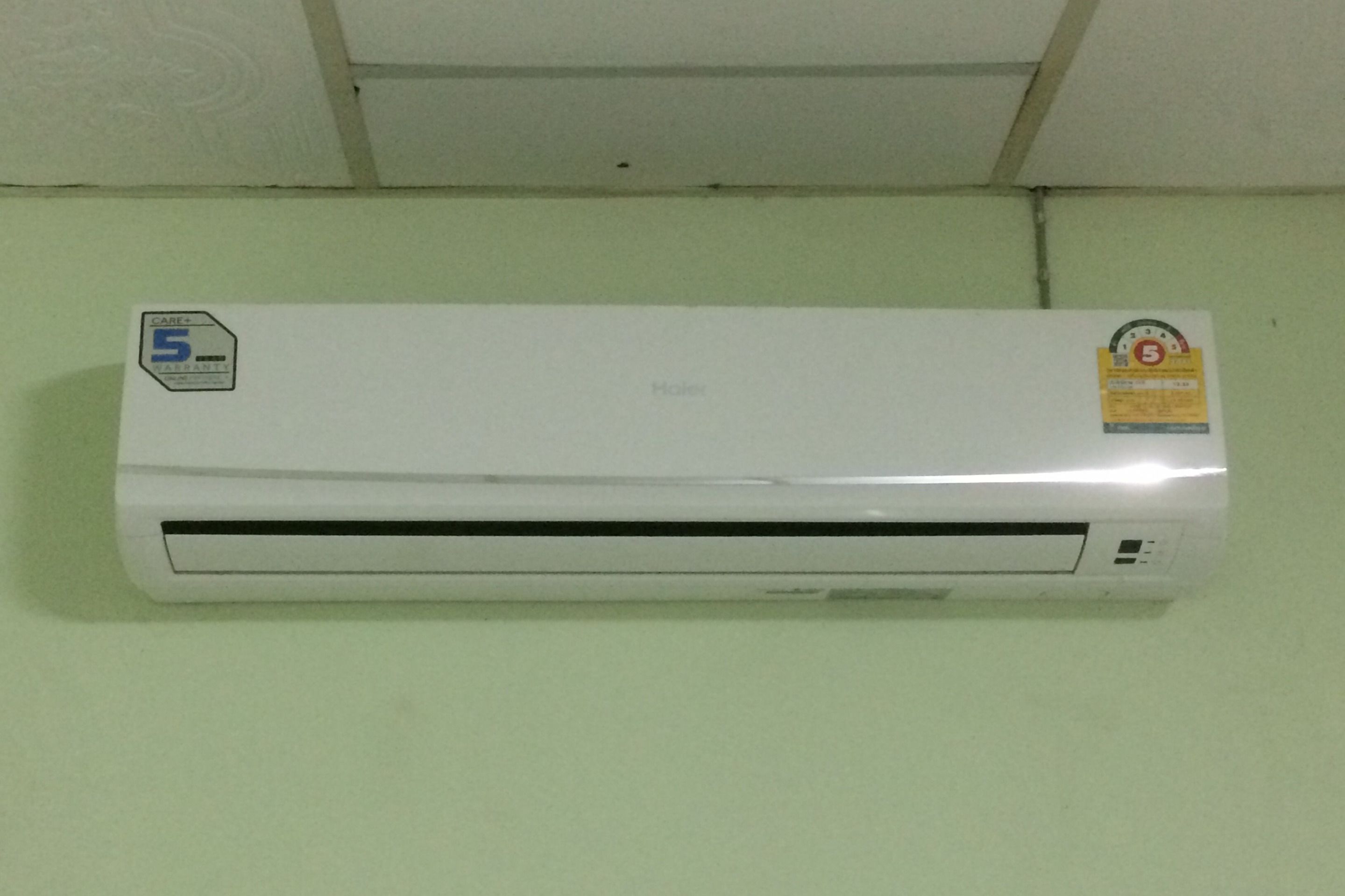 A white wall-mounted air conditioner with a Care+5 warranty sticker and a maintenance tag.
