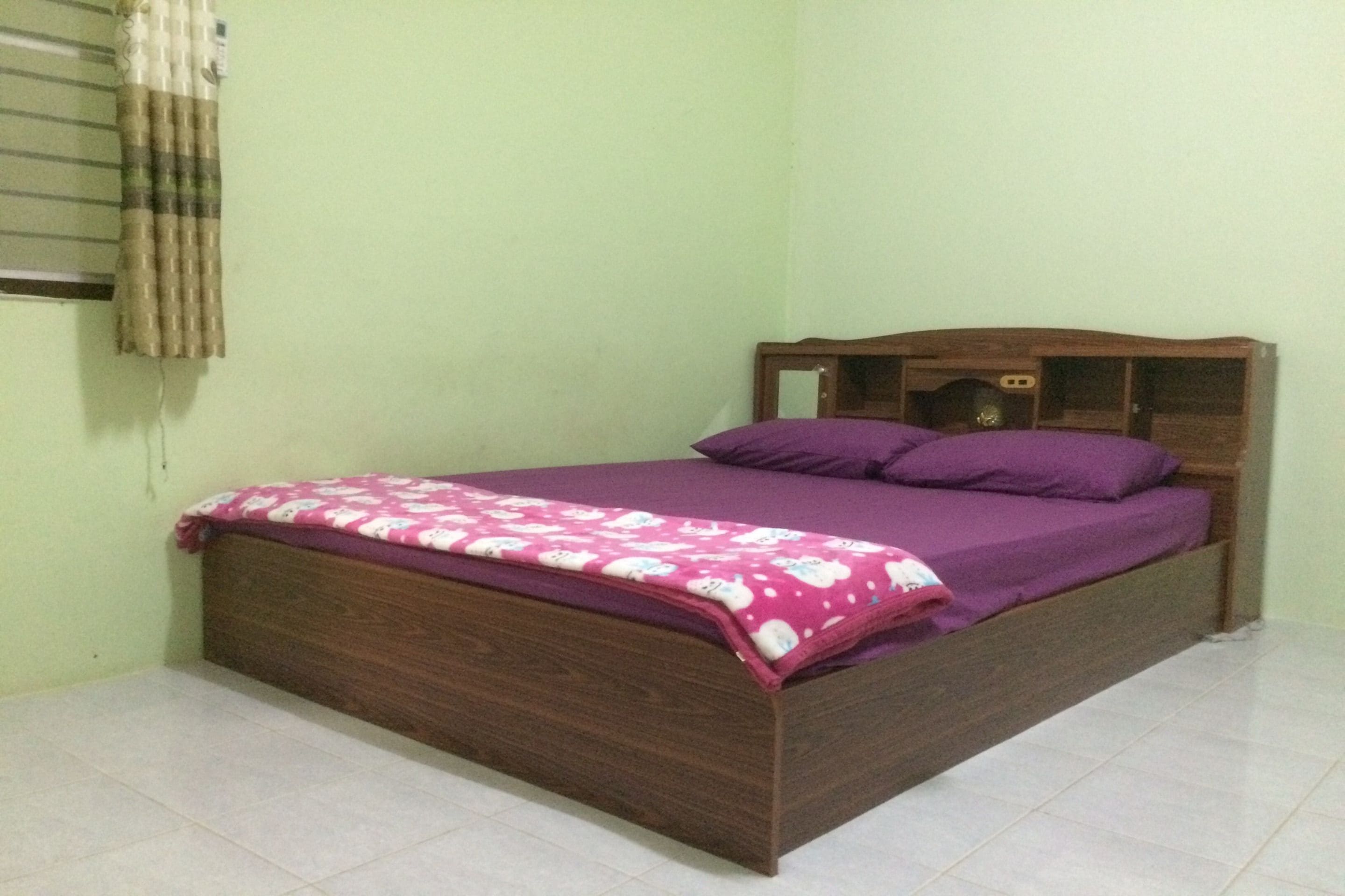 A single bed with a wooden headboard and a purple bedspread.