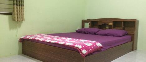 A single bed with a wooden headboard and a purple bedspread.