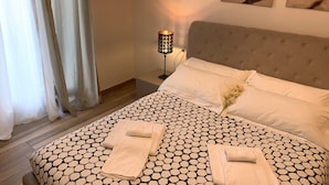 A neatly made bed with a geometric patterned bedspread, two pillows, and two folded towels. - Affittacamere Il Borgo (Levanto)