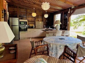 Un interior de madera con una mesa de comedor, sillas, un refrigerador y una zona de cocina.