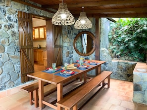 Un comedor rústico con pared de piedra, banco de madera y mesa preparada para cuatro.