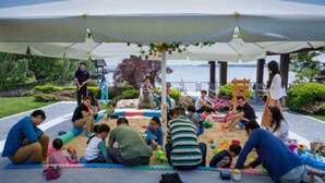A group of people sitting on mats under a canopy, with a view of the sea in the background. - Tongli Lake Resort Phase2 (Suzhou)