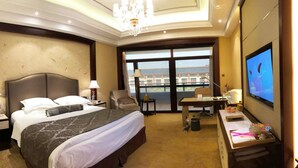 A hotel room with a large bed, a desk, a chair, a television, and a view of the city through the window. - Tongli Lake Resort Phase2 (Suzhou)
