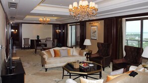 A spacious living room with a large chandelier, leather sofas, a coffee table, and a view of a cityscape through large windows. - Tongli Lake Resort Phase2 (Suzhou)