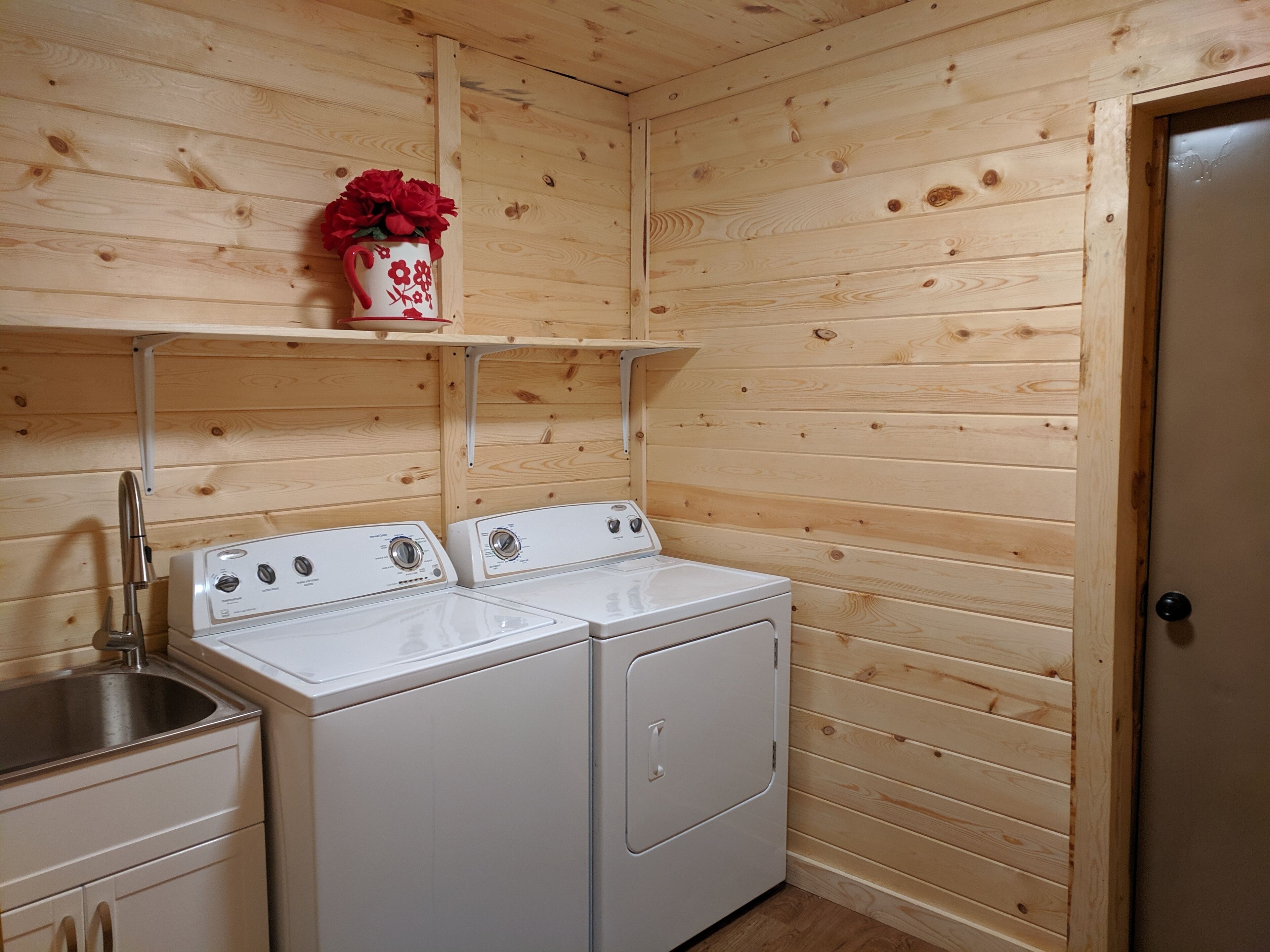 A small laundry room with two washing machines and a sink.