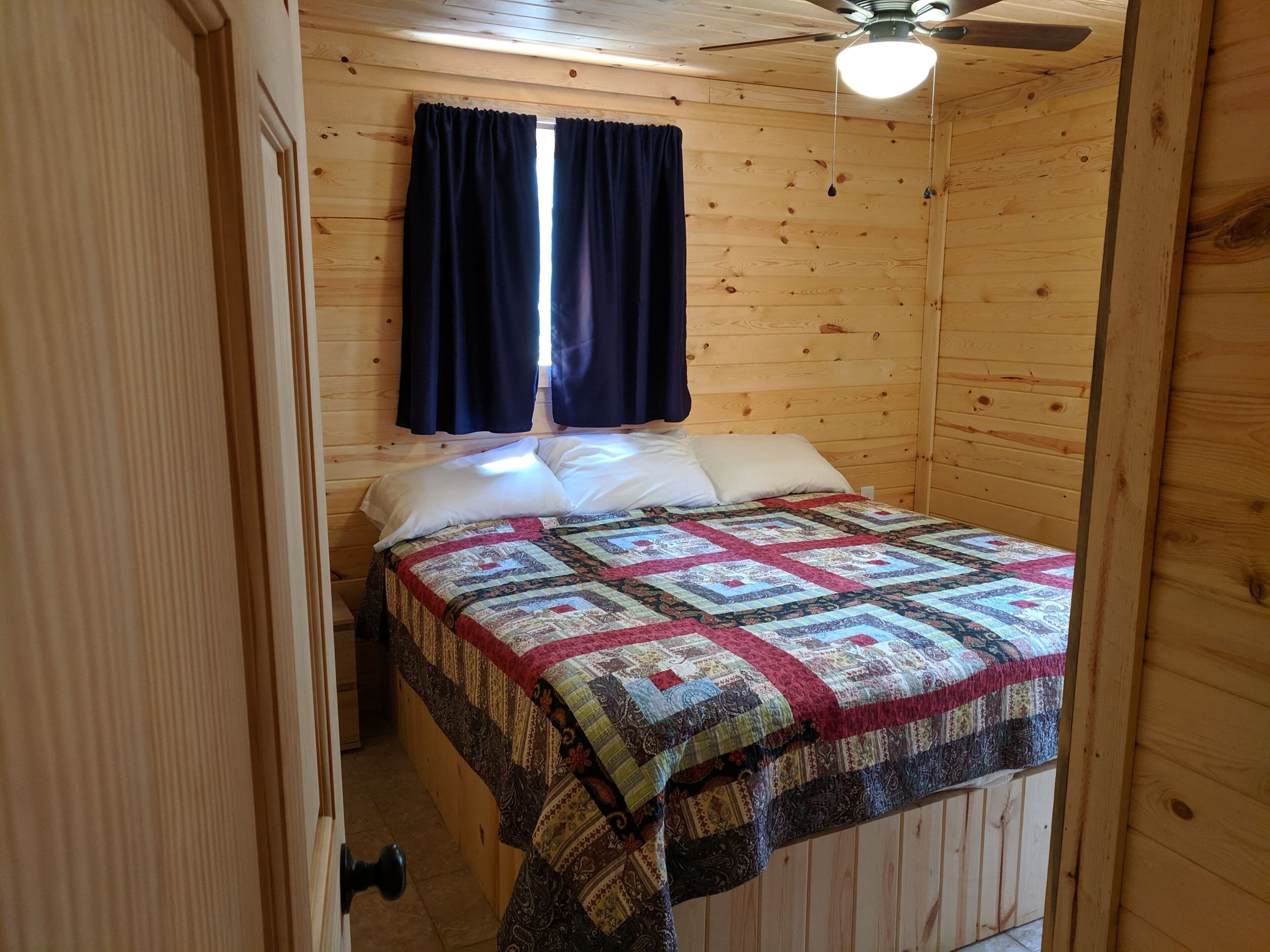 Een kleine, knusse kamer met houten wanden en een enkel bed.