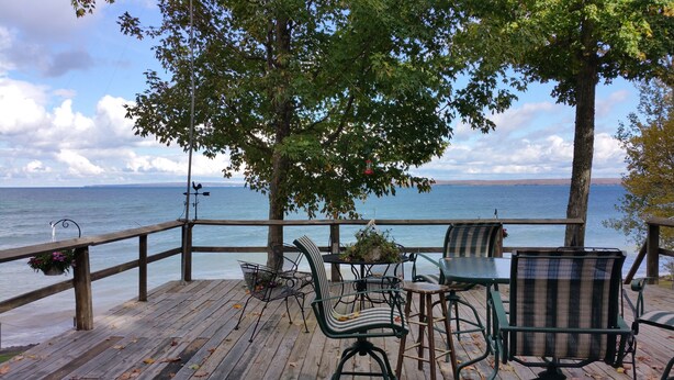 Una terraza de madera con mobiliario exterior con vistas a un lago.