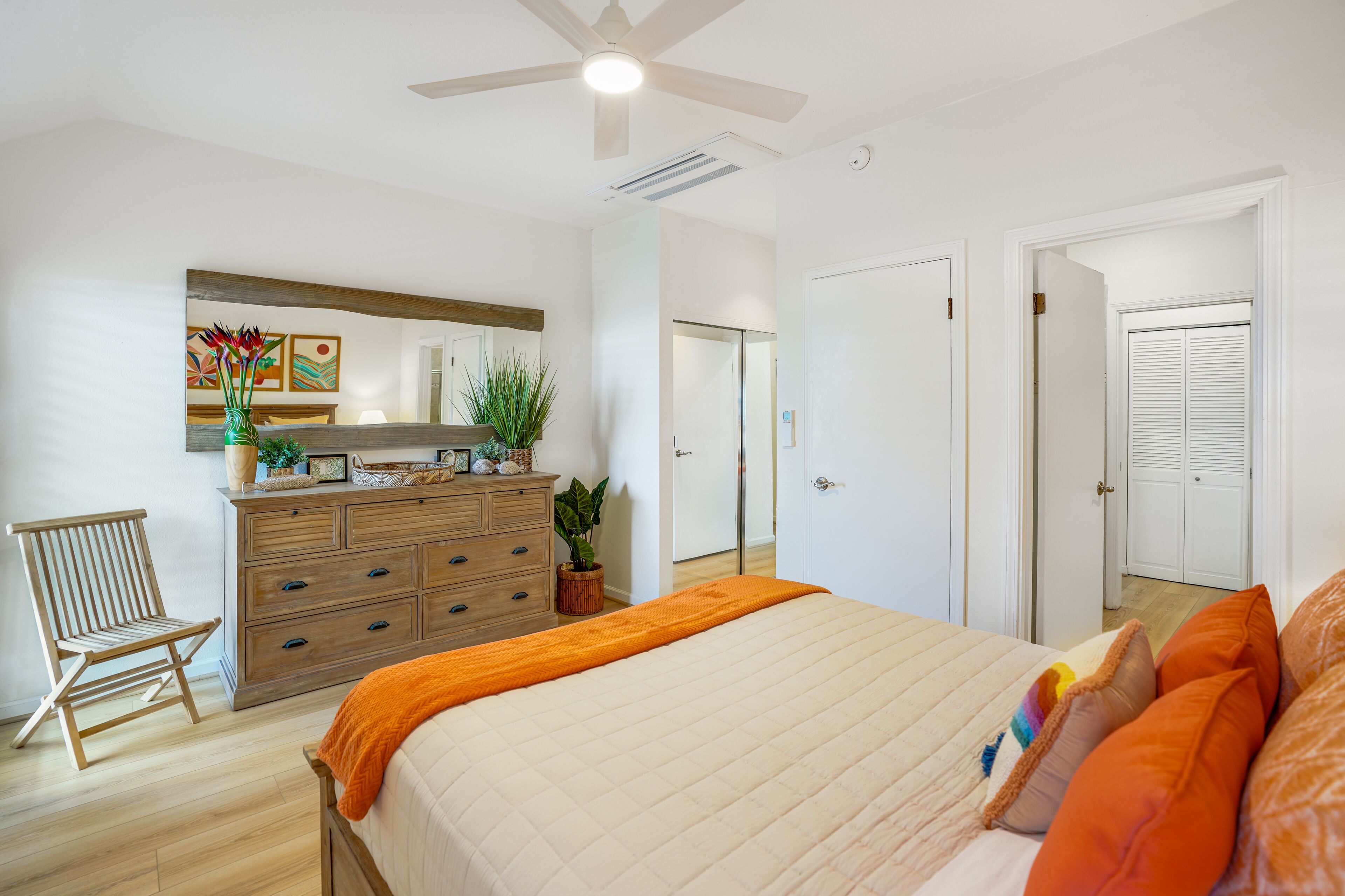 Un dormitorio con cama, cómoda, silla y ventilador de techo.