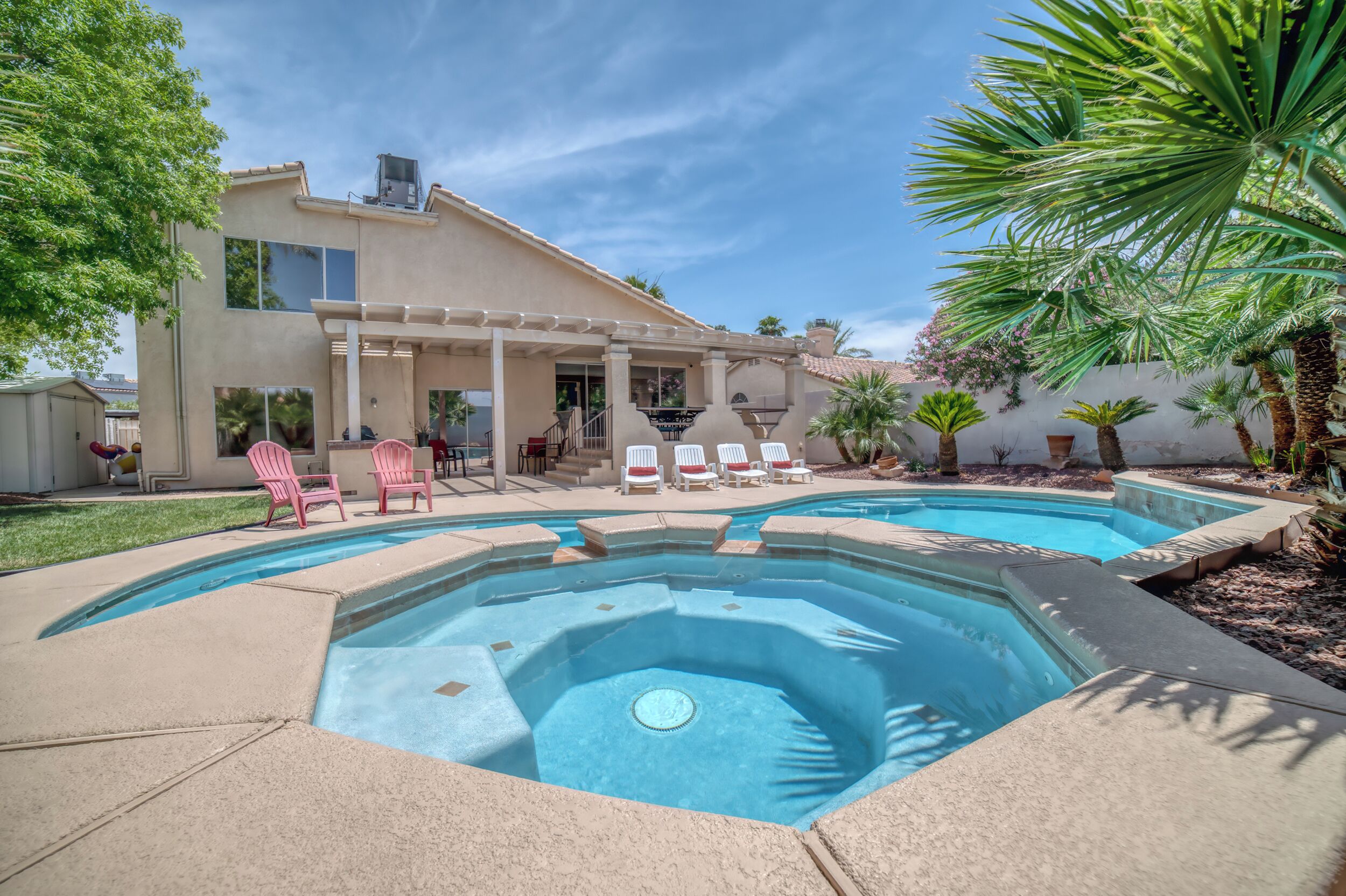 Ein Garten mit Swimmingpool, Liegestühlen und einer Pergola.