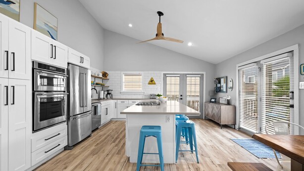 A modern kitchen with white cabinets, stainless steel appliances, and a central island with stools.