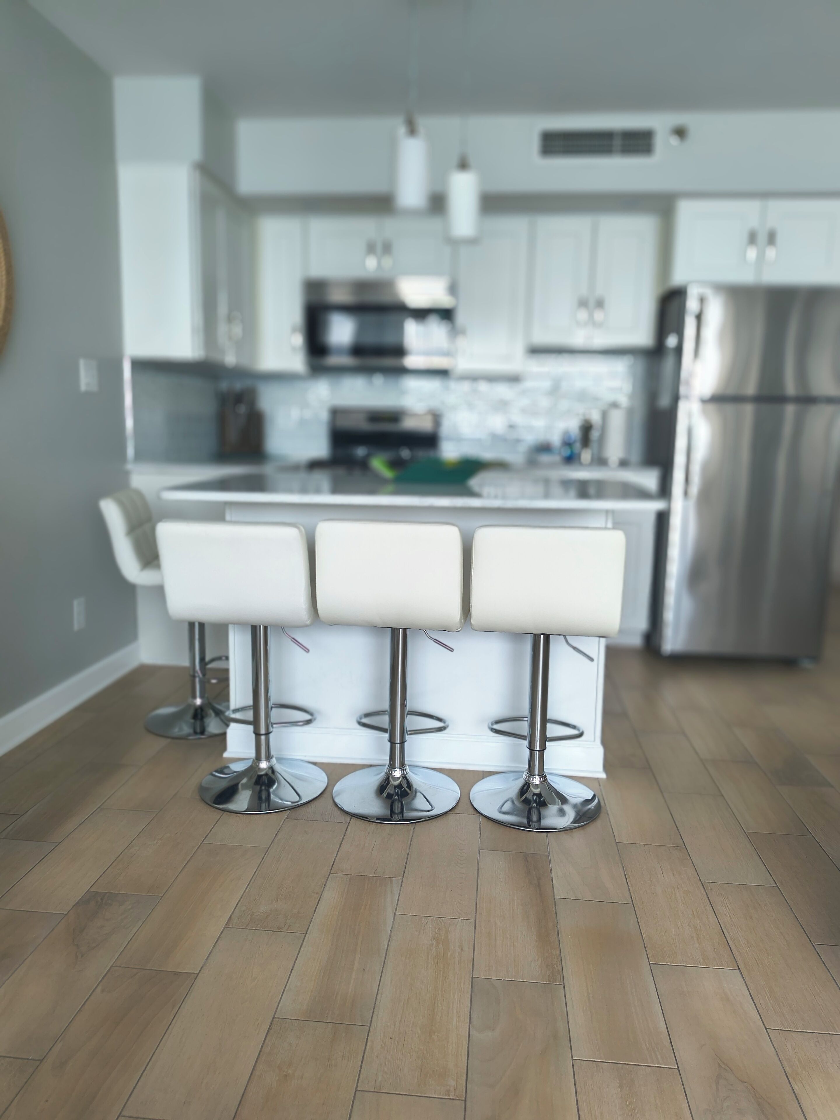 A modern kitchen with a central island, stainless steel appliances, and a bar stool area.