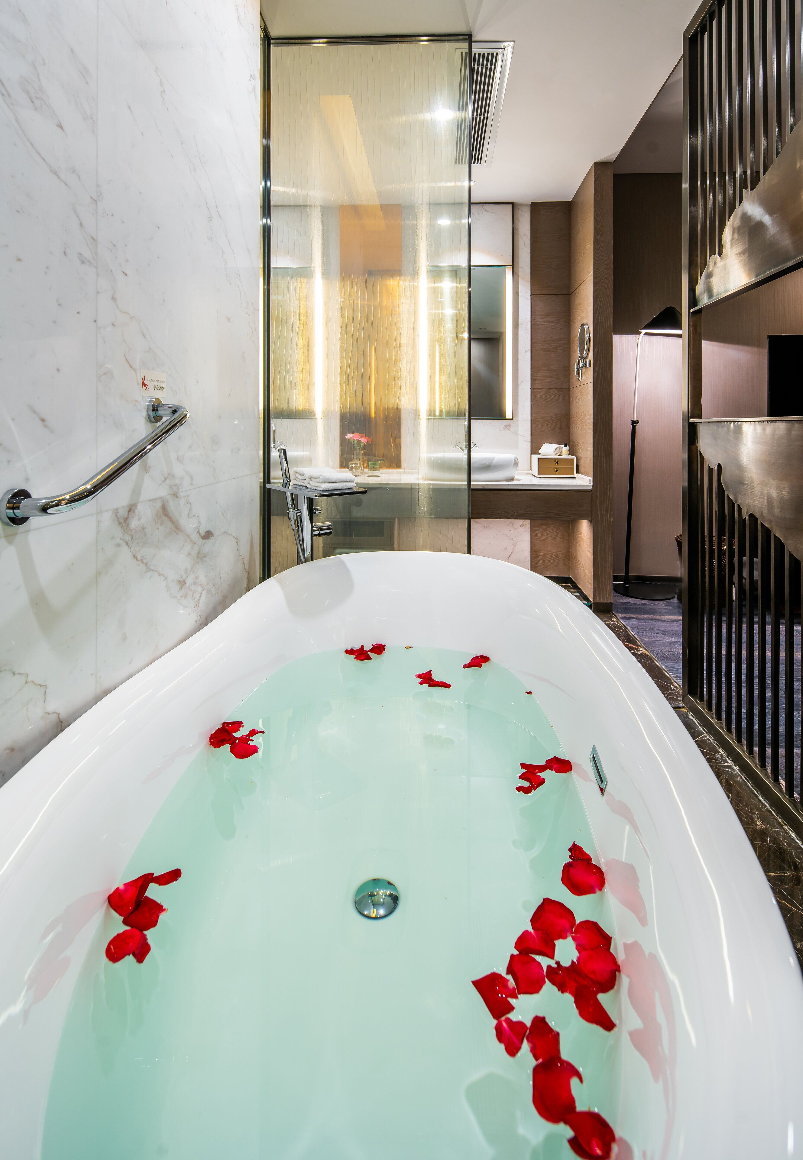 A modern bathroom with a freestanding bathtub, glass shower enclosure, and marble walls.