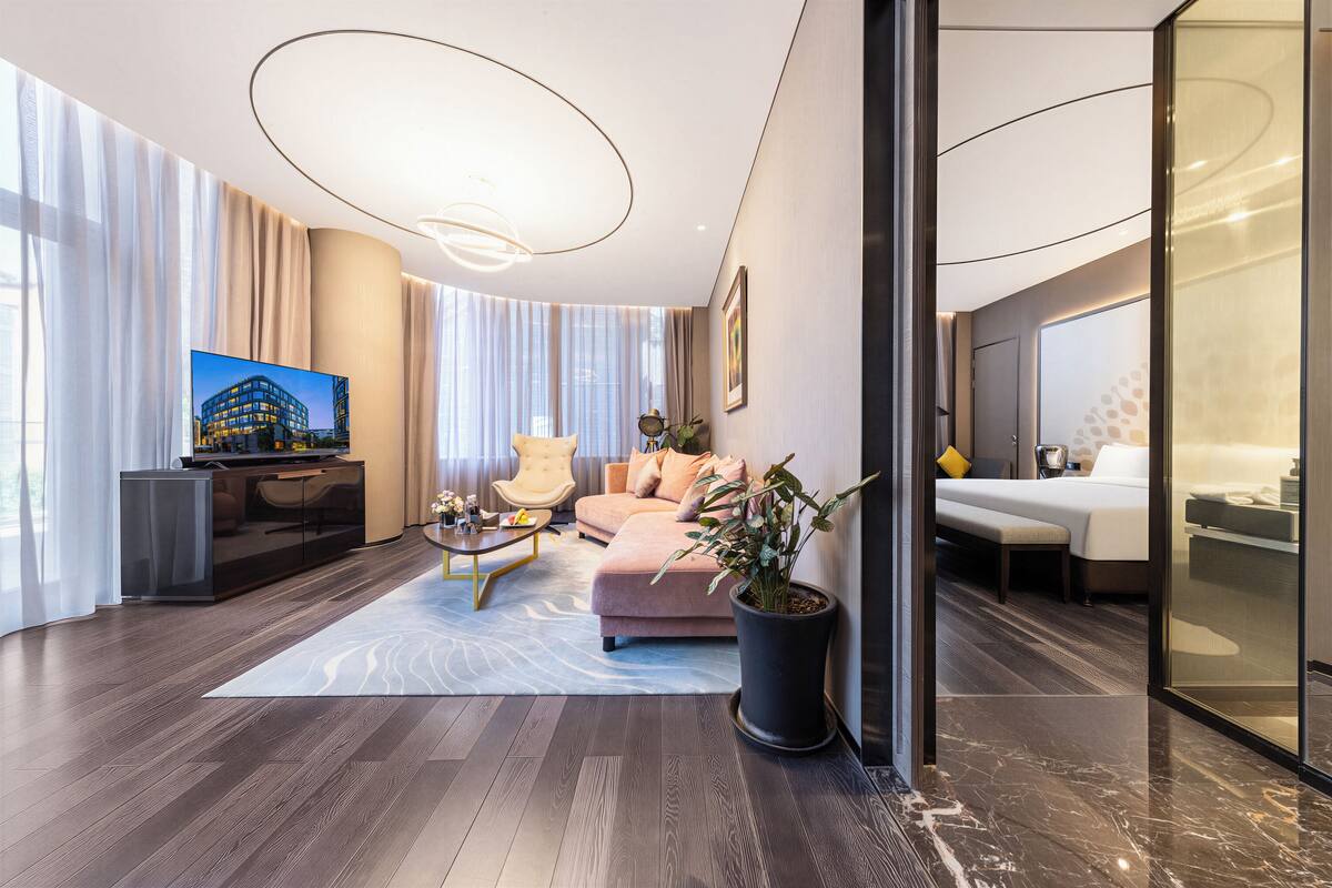A modern living room with a sofa, armchair, and a large potted plant.
