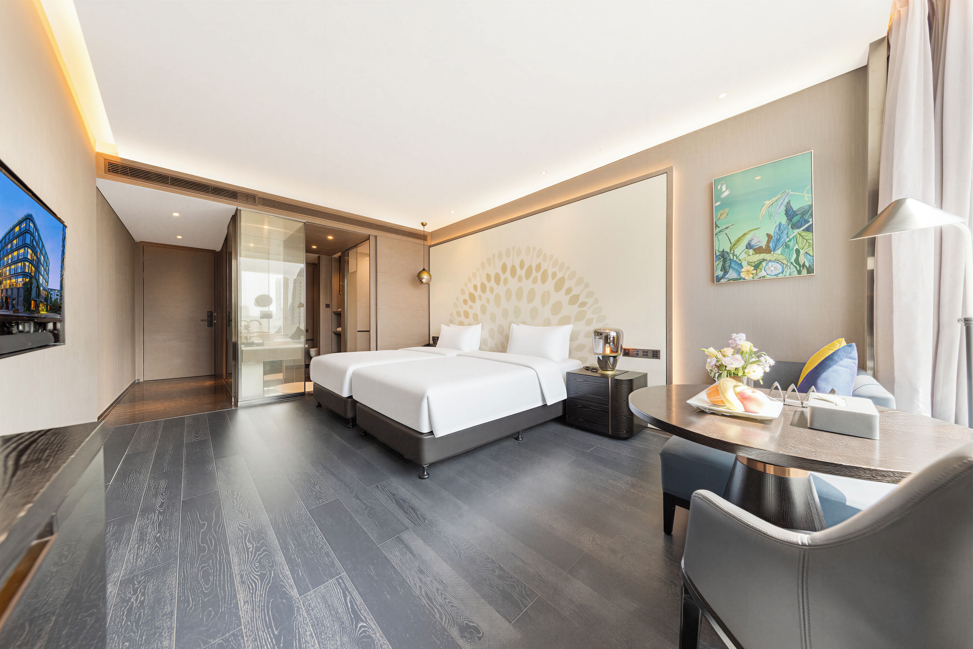 A modern hotel room with a large bed, a desk, and a glass door leading to a balcony.