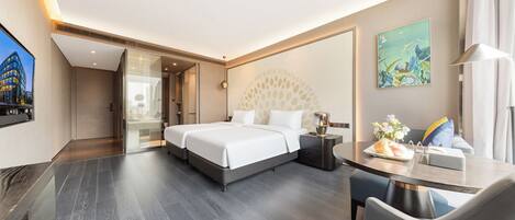 A modern hotel room with a large bed, a desk, and a glass door leading to a balcony.
