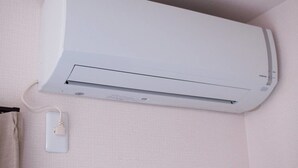 Un aire acondicionado blanco instalado en la pared, con el cable de alimentación conectado.